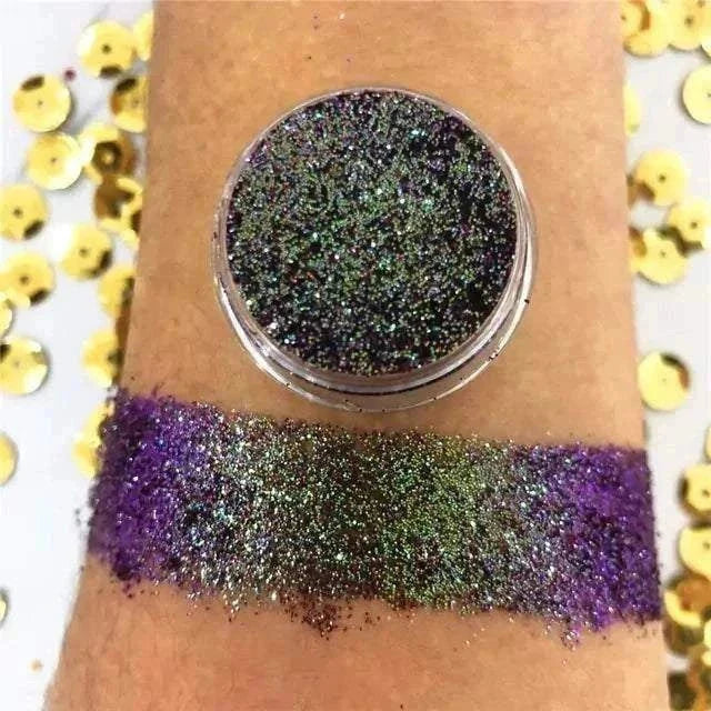 Fard à paupières en poudre pailletée multicolore, aux reflets changeants verts, violets et argentés, présenté en pot et swatché sur la peau.